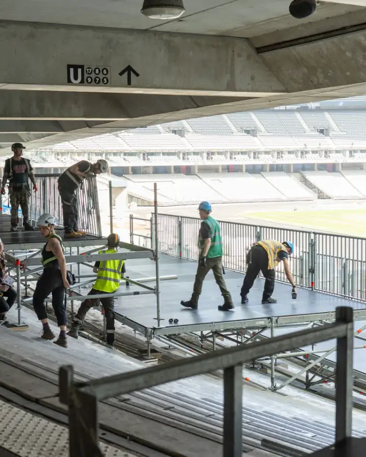 Crew members setting up a stage deck in a stadium
