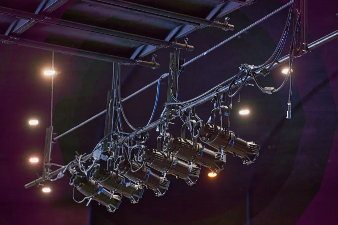 Moving lights hanging from truss above a stage