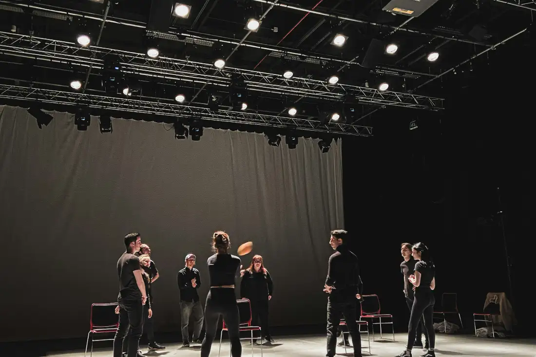 Group working together on a black-box stage under a lighting grid